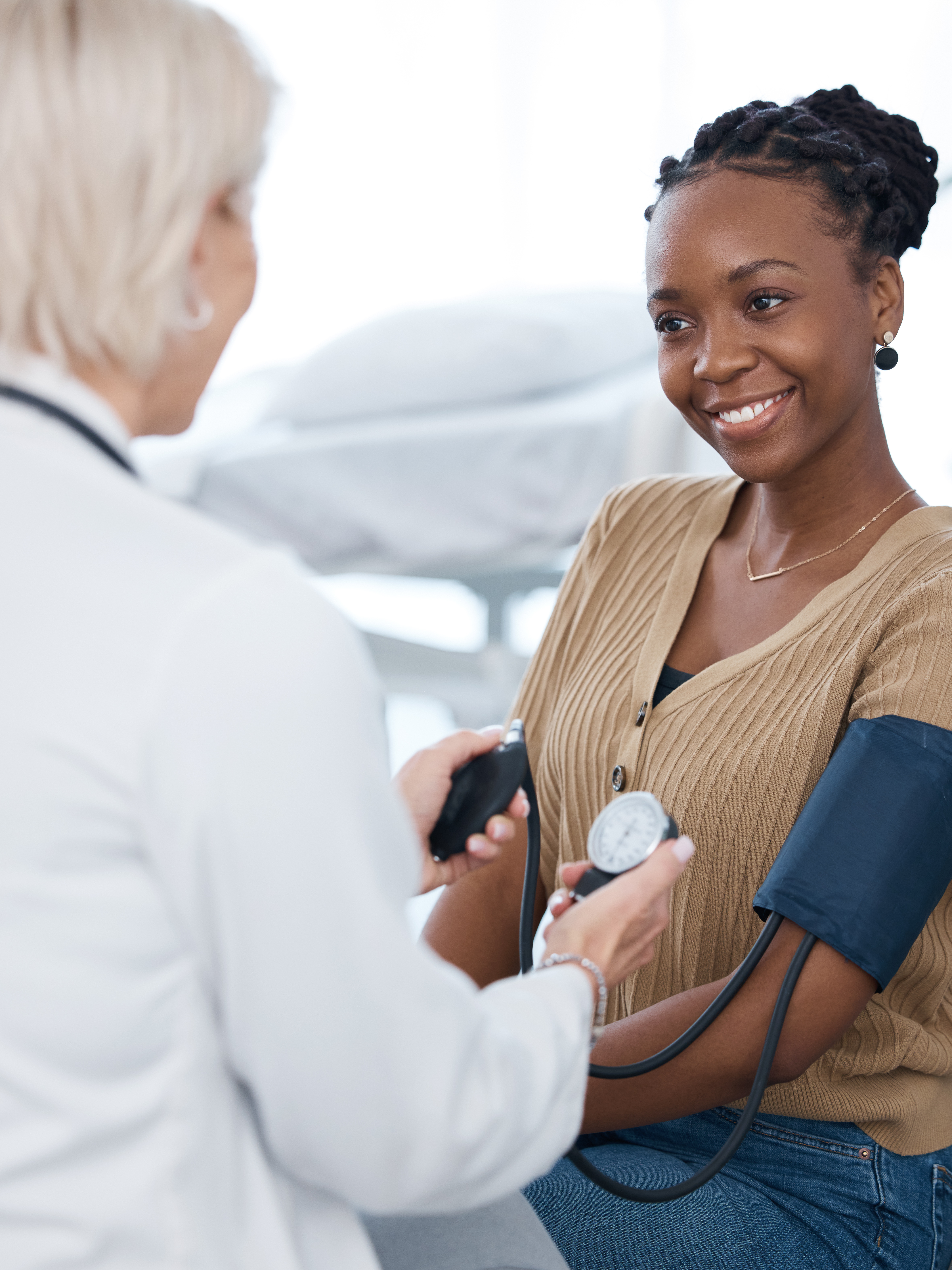Blood pressure, doctor and black woman patient smile in hospital for healthcare consulting services